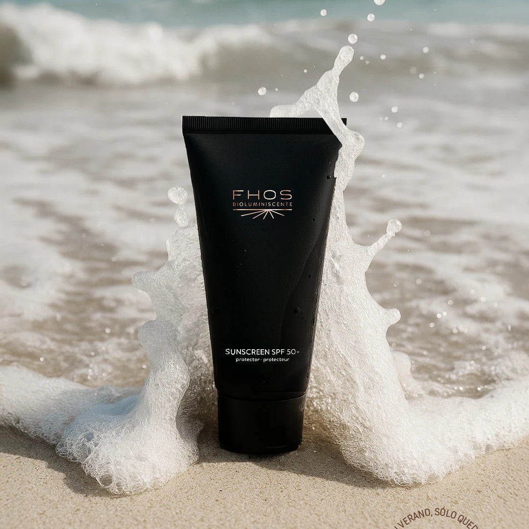 Black sunscreen tube with 'FHOS' branding on a beach with ocean waves.
